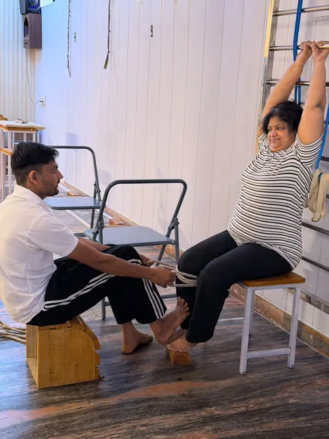 An instructor guiding a student using a chair for yoga