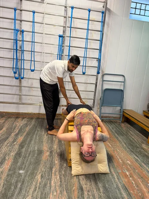 An instructor assisting a student during supported yoga practice