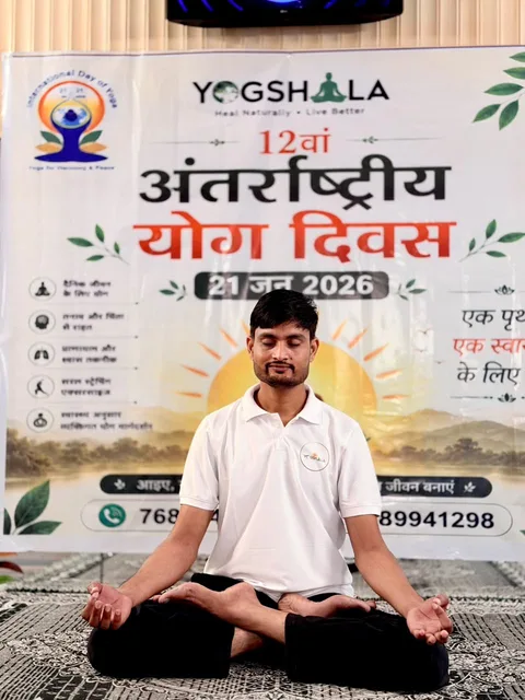 Seated yoga practice in front of the Yogshala Yoga Day banner
